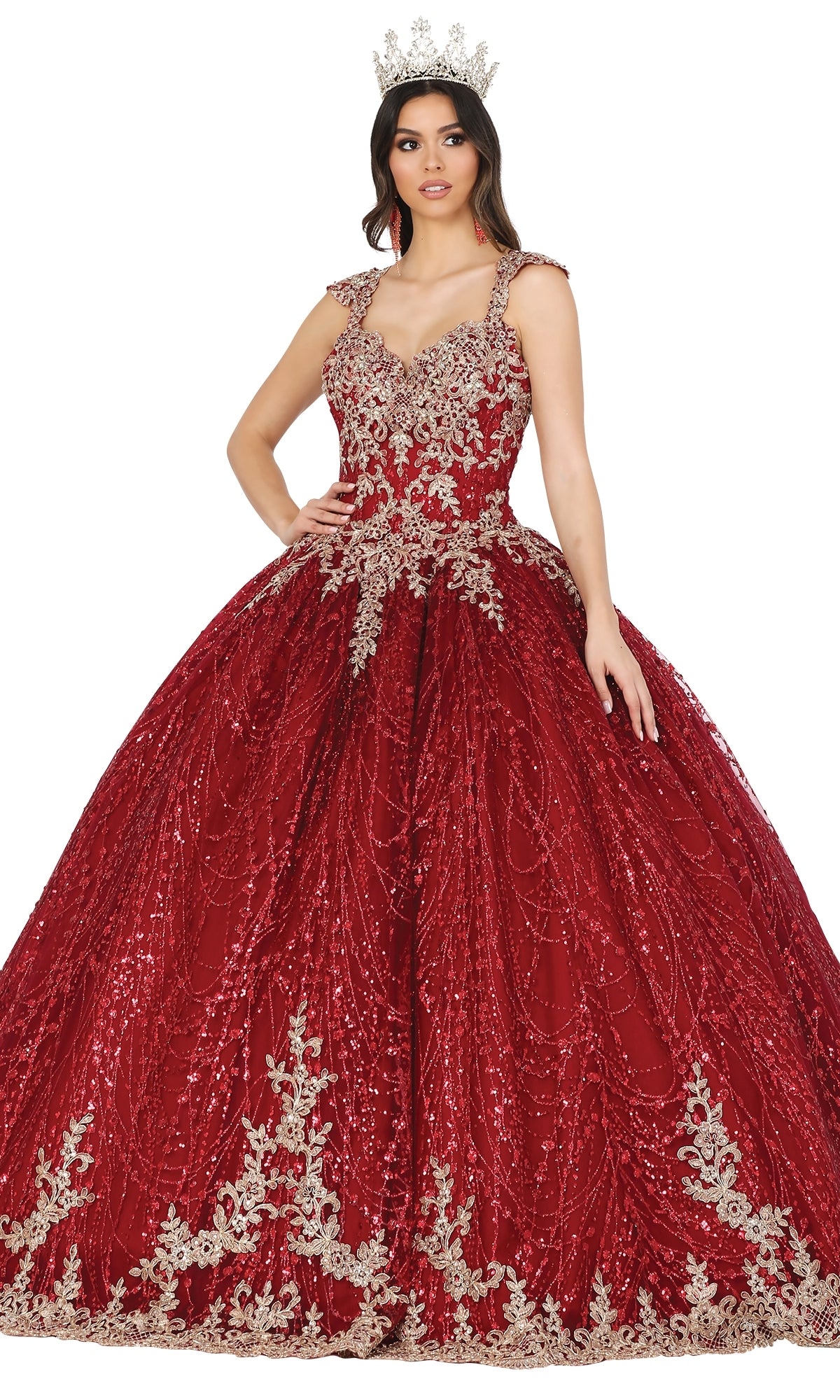 A woman stands with one hand on her hip, wearing the Quinceanera Dress 1478 by Dancing Queen—a red ball gown with a lace embroidered corset bodice, silver embellishments on the cap sleeves, and a matching silver crown.